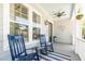 Inviting front porch with rocking chairs, striped rug, ceiling fan, and decorative hanging plants at 1536 Keshi Pearl Dr, Mount Pleasant, SC 29466