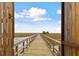 Scenic marsh view through a wooden gate showing the long boardwalk leading to a private island at 1536 Keshi Pearl Dr, Mount Pleasant, SC 29466