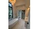 Bright bathroom featuring a soaking tub under a window with a separate glass-enclosed shower and dual vanity at 1727 Atlantic Ave, Sullivans Island, SC 29482
