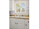 Close-up of a kitchen sink with white cabinets and a window view at 19 Rudwick Cir, Goose Creek, SC 29445