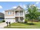 Charming two-story home with a front porch, balcony, manicured lawn, and a two car garage at 200 Topsaw Ln, Moncks Corner, SC 29461