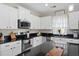 Bright kitchen features white cabinets, black granite countertops, stainless steel appliances and a breakfast bar at 200 Topsaw Ln, Moncks Corner, SC 29461