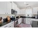 Well-lit kitchen boasts white cabinets, stainless steel appliances, black countertops, and hardwood floors at 200 Topsaw Ln, Moncks Corner, SC 29461