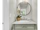 Bright powder room featuring white countertops, round mirror, modern faucet, and stylish decor at 220 Runnymede Ln, Summerville, SC 29485