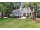 Inviting one-story home with well-manicured lawn, mature trees, and a welcoming front porch with beautiful garden at 220 Runnymede Ln, Summerville, SC 29485