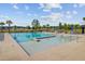 Community pool with zero entry, splash pad, and lounge seating, surrounded by lush greenery and black aluminum fencing at 325 Coral Sunset Way, Summerville, SC 29486