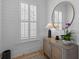 Stylish entryway with a round mirror, elegant console table, and natural light from a shuttered window at 3870 Fifle St, Mount Pleasant, SC 29466