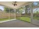 A screened-in porch with a ceiling fan offers a view of the green backyard and wooden fence at 4949 Serene Ln, Hollywood, SC 29449