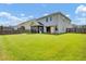 View of the home's spacious backyard with a screened-in porch, ample green space, and a privacy fence at 613 Ravens Wood Rd, Summerville, SC 29486