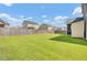 Large fenced backyard featuring lush green grass and partial view of neighboring homes under a blue sky at 613 Ravens Wood Rd, Summerville, SC 29486