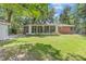 Expansive backyard featuring lush green lawn, mature trees, and a brick home with a wall of windows at 112 Roselle Ave, Goose Creek, SC 29445