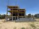 Under construction; multi-level home on a sandy lot under a sunny blue sky, framed with unfinished wood and scaffolding at 2879 Marshall Blvd, Sullivans Island, SC 29482