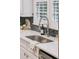 Close-up of kitchen sink, faucet, white countertops, white cabinets, and tile backsplash at 2911 Old Tavern Ct, Mount Pleasant, SC 29466