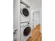 Hallway laundry closet with stacked washer and dryer in hallway featuring hardwood floors and a white door at 415 Parkdale Drive # E-8, Charleston, SC 29414