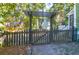 A rustic backyard featuring a wooden gate and trellis surrounded by mature trees and lush greenery at 794 Hunt Club Run, Charleston, SC 29414