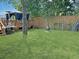 Backyard with wooden fence, green grass, a fire pit, and a covered deck at 8496 Roanoke Dr, North Charleston, SC 29406