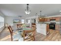 Open dining area with a glass table, hardwood floors and a view of the kitchen and living spaces at 7034 Lanier St, Hanahan, SC 29410