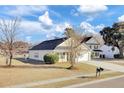 Tan house with a black roof, white garage door, and landscaping at 1112 Moss Grove Dr, Moncks Corner, SC 29461