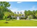 Two-story white house with gray metal roof, front porch, and lush landscaping at 2972 Anchor Watch Dr, Wadmalaw Island, SC 29487