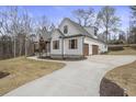 White farmhouse with attached garage and long driveway, nestled amongst trees at 7210 Raw Dew Dr, Awendaw, SC 29429