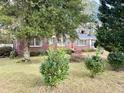 Brick ranch house with red door, nicely landscaped yard, and large trees at 201 Center St, Walterboro, SC 29488