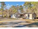Tan mobile home with covered porch, American flag, and gravel driveway at 250 W Medina St, Summerville, SC 29483