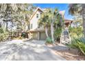 Home with two-car garage and elevated deck, surrounded by trees at 119 Halona Ln, Kiawah Island, SC 29455