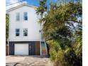 Two-story white house with colorful stairs and garage at 79 Sandbar Ln, Folly Beach, SC 29439