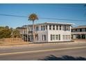 Two-story beach house with white siding, black shutters, and a deck at 405 Palmetto Blvd, Edisto Island, SC 29438