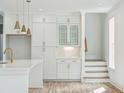 Bright white kitchen with an island and gold accents, hardwood floors and staircase at 4430 Beaver St, North Charleston, SC 29405