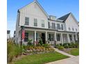 White farmhouse-style home with a porch, brick accents and nicely landscaped garden at 1011 Swamp Harrier Ave, Ravenel, SC 29470