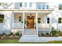 White porch with wooden door, railing, and potted plants at 362 6Th Ave, Mount Pleasant, SC 29464