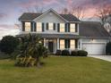 Two-story house with green shutters, white siding, and a two-car garage, at dusk at 173 Hainsworth Dr, North Charleston, SC 29418