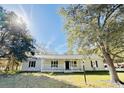 White house with a front porch, and large trees in the yard at 1966 Suzanne St, Johns Island, SC 29455