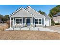 Gray house with blue door, rocking chairs on porch, and landscaped yard at 1290 Palm Cove Dr, Charleston, SC 29492
