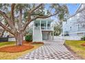 Two-story light blue house with white trim, a front porch, and a landscaped yard at 1442 Eutaw Battalion Dr, Charleston, SC 29412
