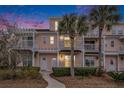 Three-story peach building with white trim, balconies, and palm trees at dusk at 2978 Sugarberry Ln, Johns Island, SC 29455