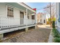 Side view of a charming white cottage with a long front porch and brick pathway at 17 H St, Charleston, SC 29403
