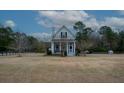 House with wrap-around porch, American flag, and spacious yard at 1104 Hitchfield Ln, Awendaw, SC 29429