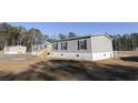 Side view of a manufactured home with gray siding and wooden steps at 120 Wilder Rd, Saint Stephen, SC 29479