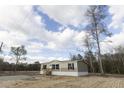 Tan and beige single-wide manufactured home with black windows, wooden steps, and surrounding woodland at 520 Branch Bend Way, Cross, SC 29436