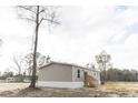 Side view of a tan manufactured home with black windows and wooden steps at 520 Branch Bend Way, Cross, SC 29436