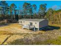 Side view of a manufactured home with a deck and surrounding trees at 240 Carolina Dr, Saint Stephen, SC 29479