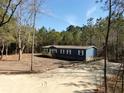 Charming single-story home with blue siding, white trim, and a cozy front porch surrounded by a wooded landscape at 355 Dike Rd Rd, Bonneau, SC 29431