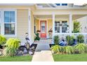 Inviting front porch with red door, white rocking chairs, and colorful plants at 203 Oak View Way, Summerville, SC 29483
