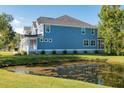 Two-story house with gray siding, a metal roof, and a backyard pond at 748 Maynard Ln, Summerville, SC 29486