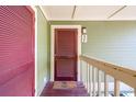 Exterior entry door with welcome mat, on a wood floor balcony at 7000 Palmetto Dr # 3F, Isle of Palms, SC 29451