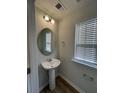 Small bathroom with pedestal sink, round mirror, and window with blinds at 413 Trotters Ln, Moncks Corner, SC 29461