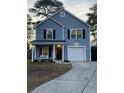 Two-story light blue house with a white garage door and front porch at 8781 Red Oak Dr, North Charleston, SC 29406