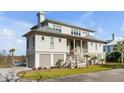 Two story house exterior with light colored siding, metal roof and a detached garage at 2618 Raven Dr, Sullivans Island, SC 29482